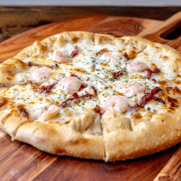 MOMO Craft Pizza's shrimp and sun-dried tomato pizza with white sauce on a wooden board.